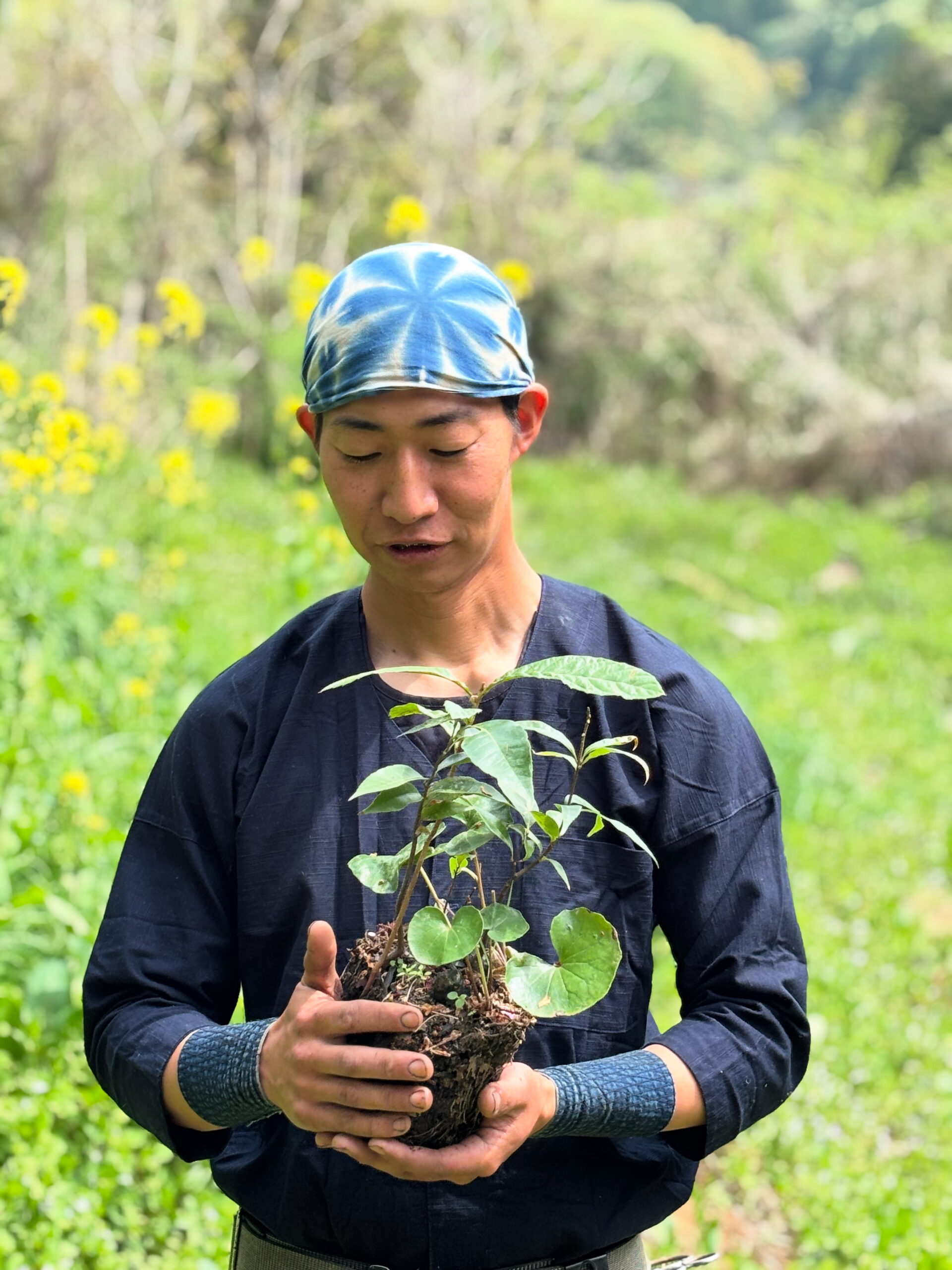 草木と根のついた土を手に持つ中山佳樹