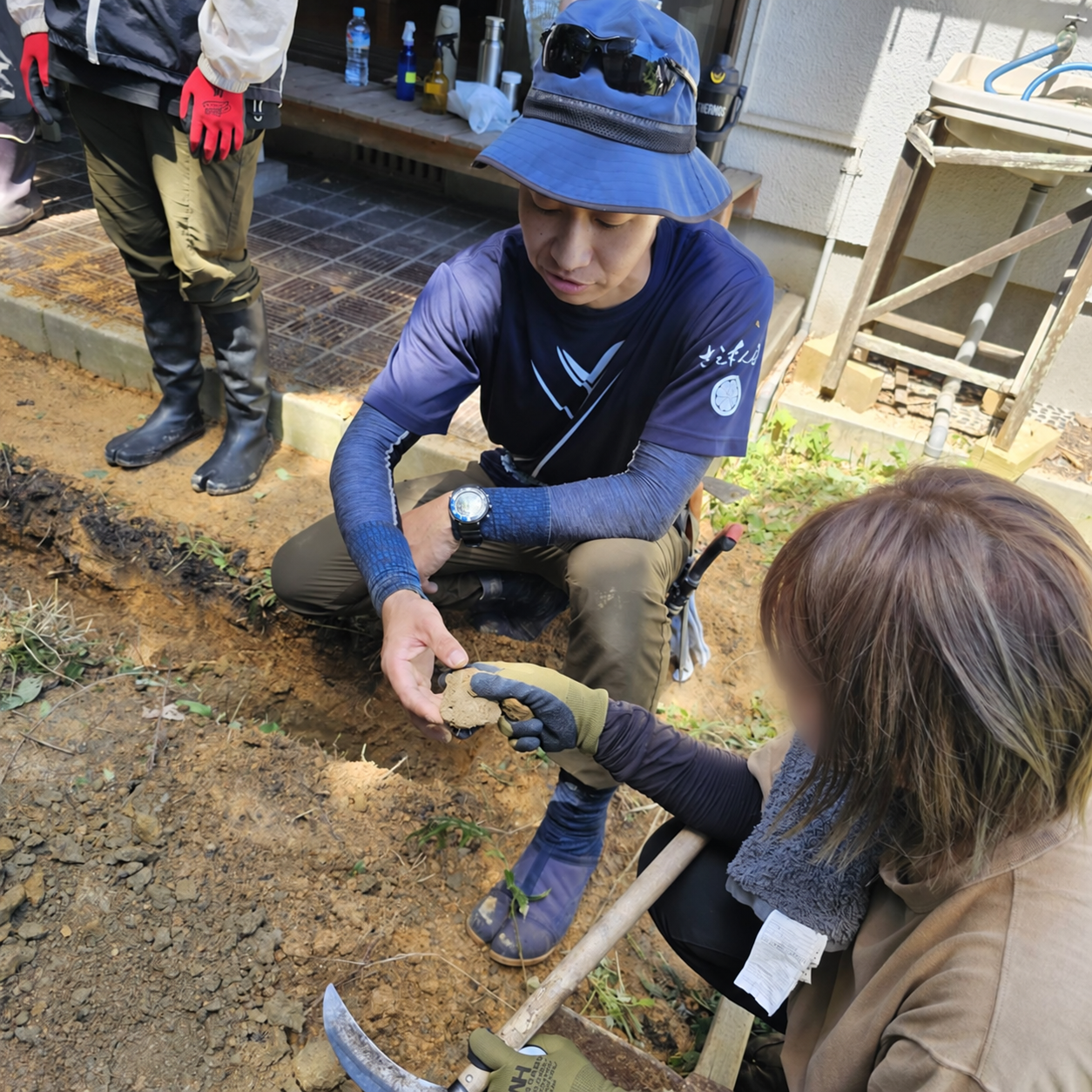 土を手に取り、状態を確かめながら説明する様子