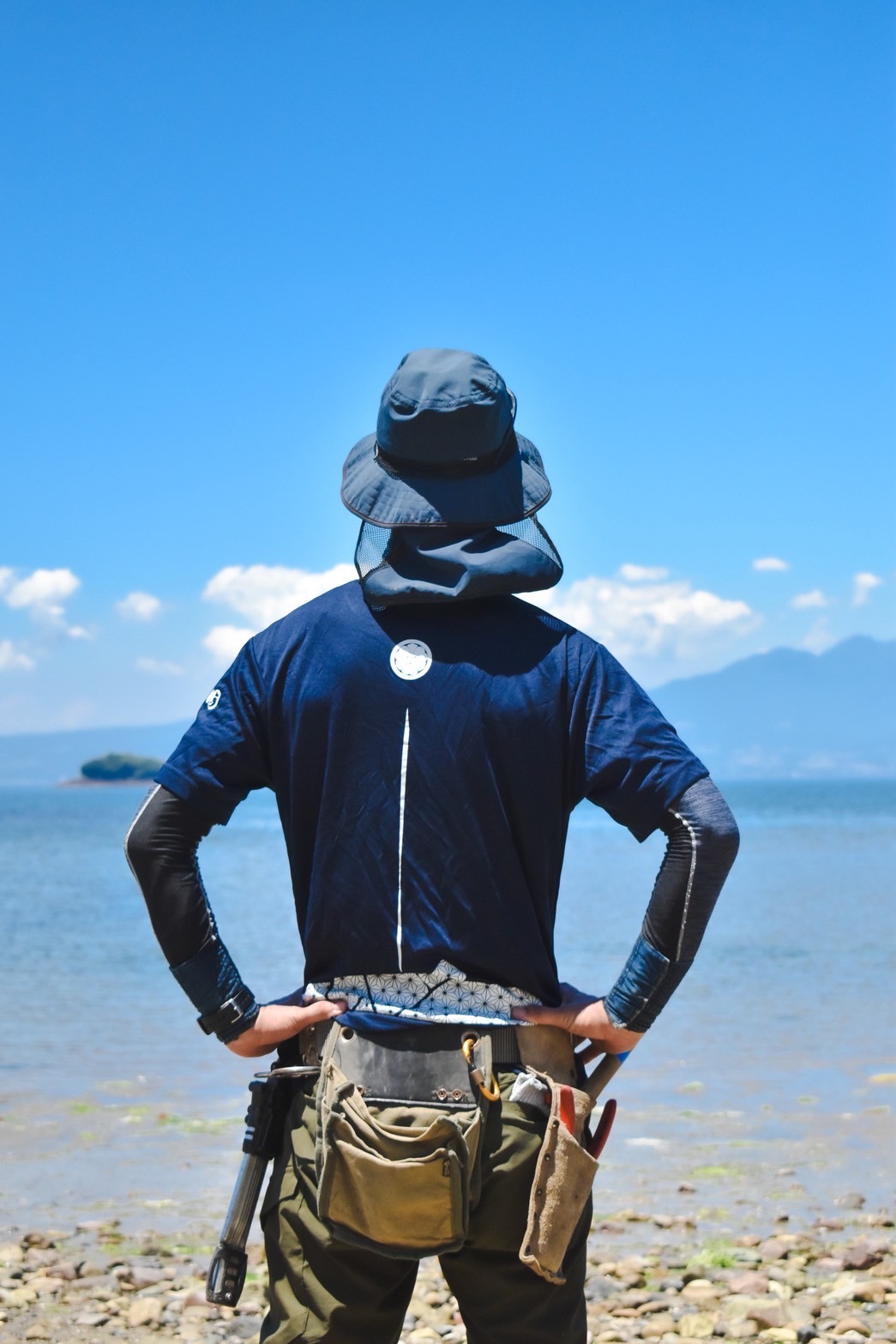 海と山を前に立つ、さえもん園の庭師