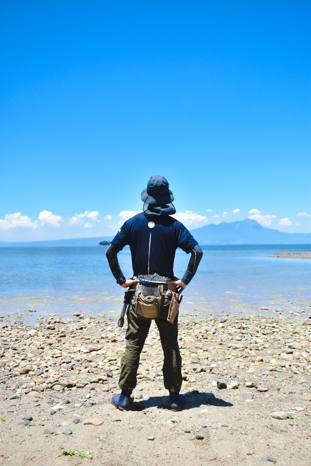 海と山を前に立つ、さえもん園の庭師